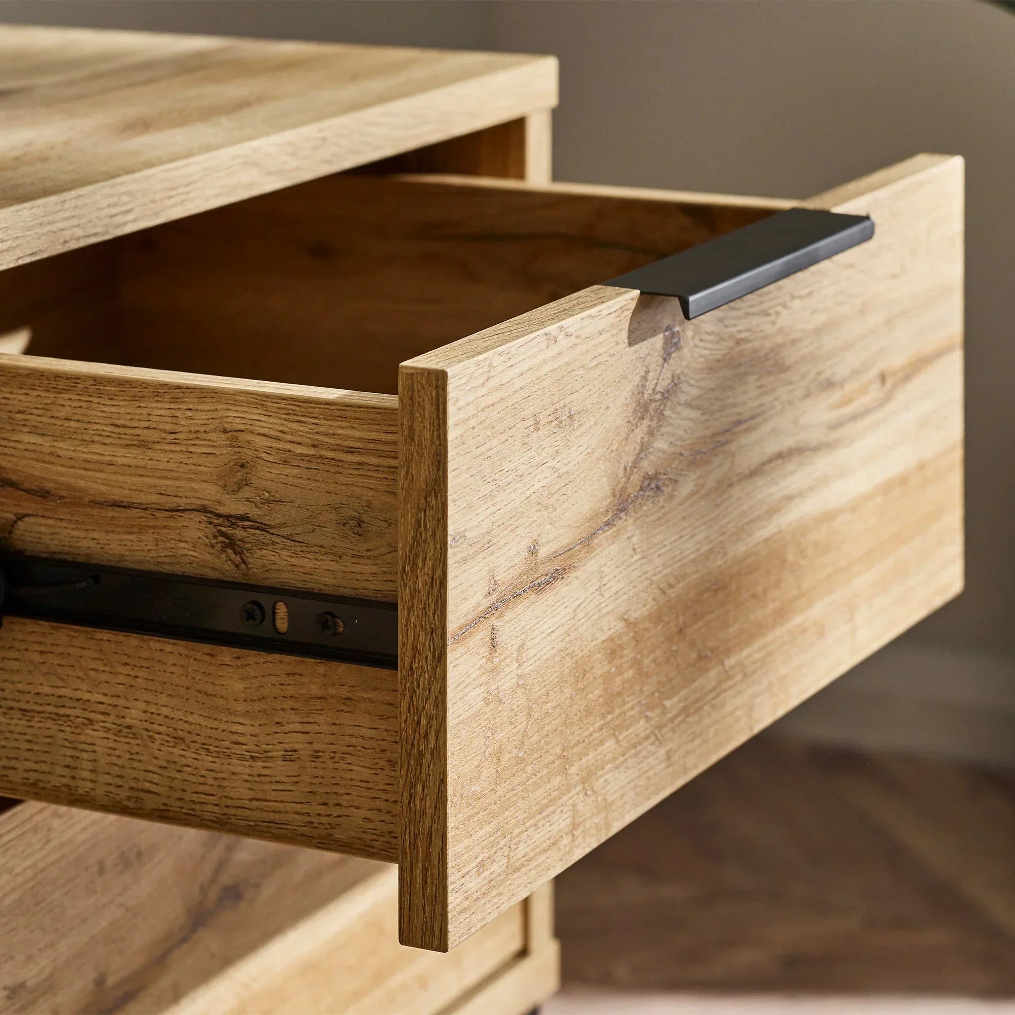 Light oak TV unit drawer with black handle shown open, highlighting wood grain texture