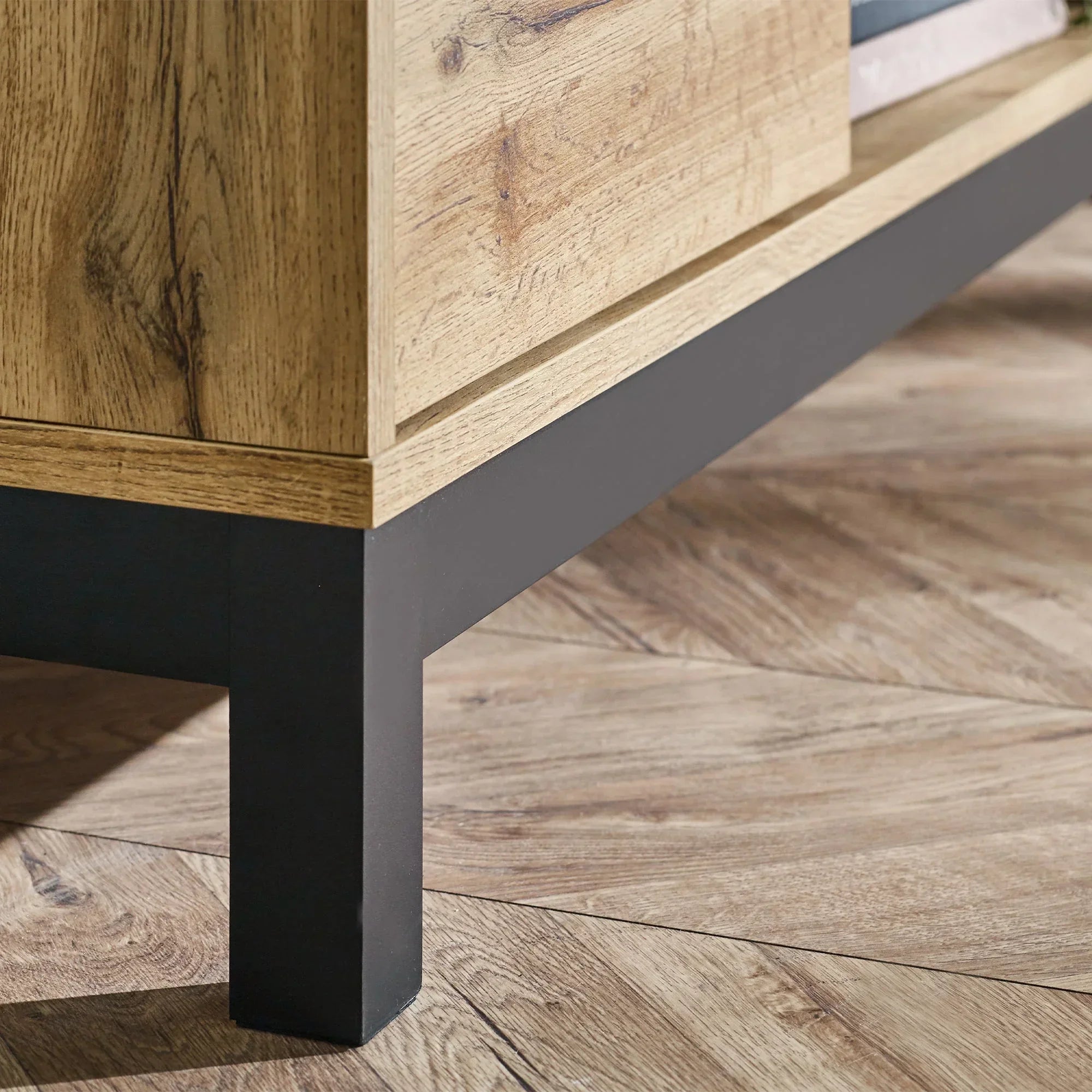 Light oak TV unit corner with black metal leg on wood floor