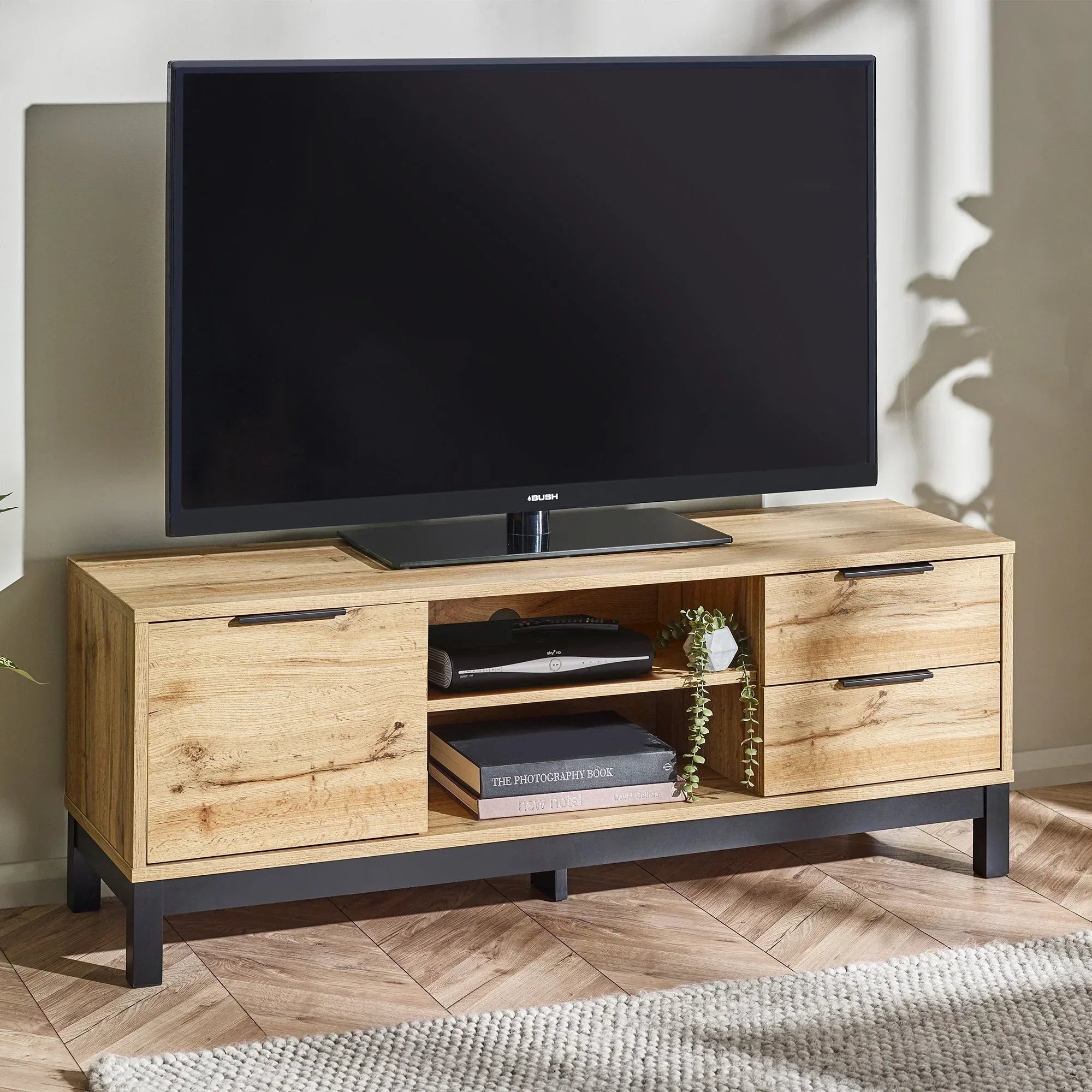 Light oak TV unit with black legs, center shelf, drawers, and storage in living room