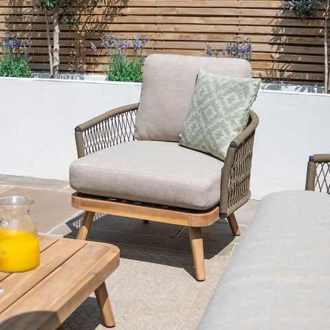 Outdoor garden armchair with beige cushions, rope sides, and wood frame on patio