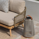 Outdoor rope sofa with beige cushions and decorative lantern on patio tiles