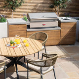 Outdoor wooden patio dining set with round table, rattan chairs, and built-in gas barbecue