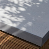 Close up of concrete outdoor table top with slatted wood base in natural sunlight