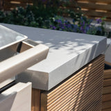 Close view of outdoor kitchen countertop with concrete top and wooden slatted panel