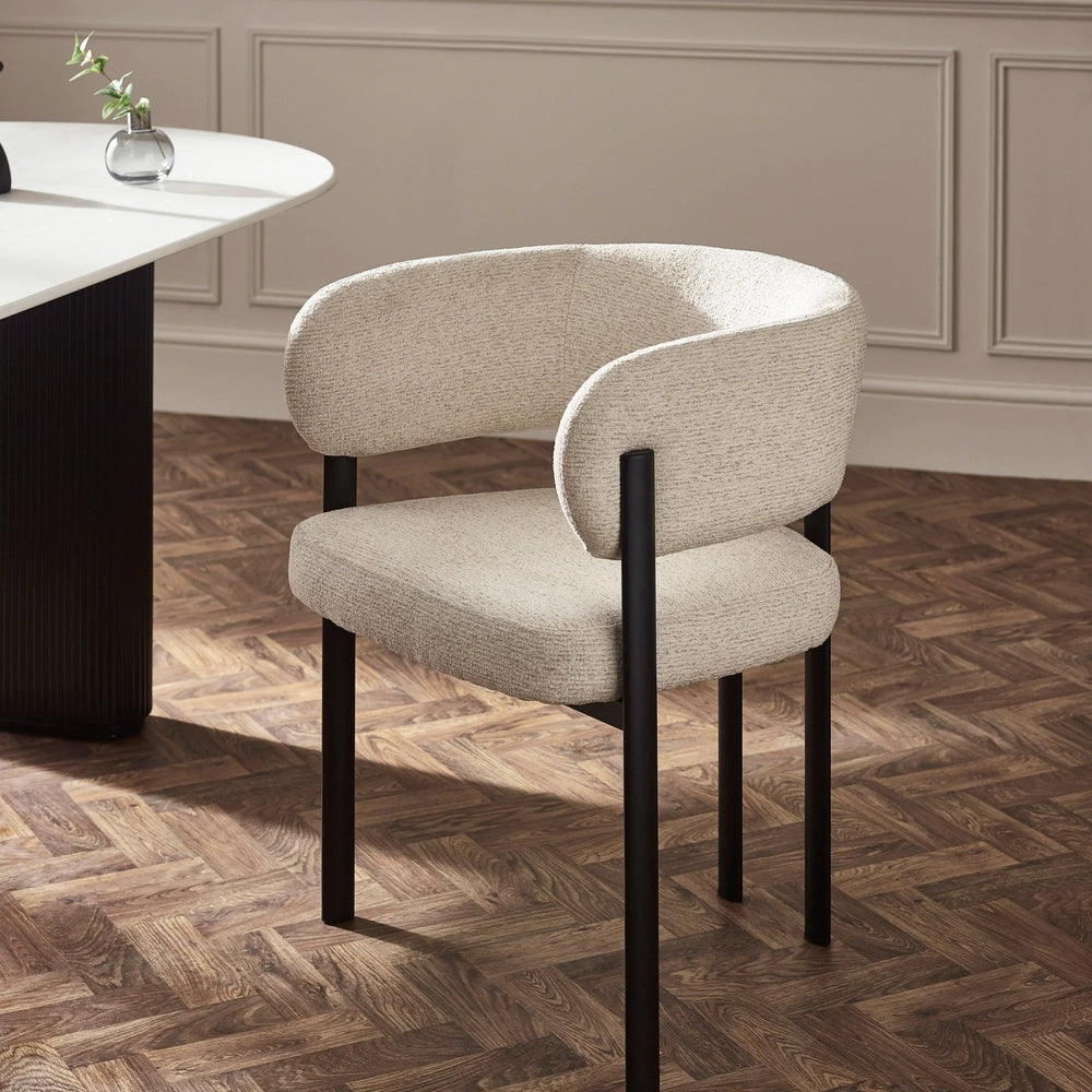 Beige upholstered dining chair with black metal legs beside white dining table on parquet floor