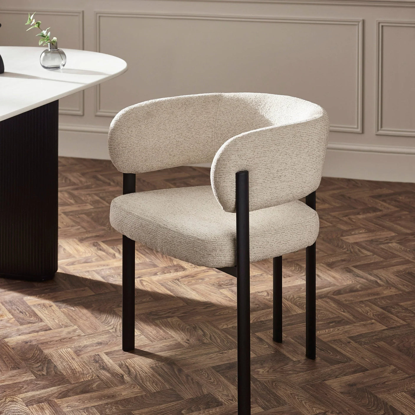 Beige upholstered dining chair with black metal legs beside white dining table on parquet floor