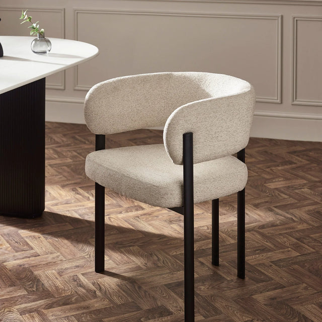 Beige upholstered dining chair with black metal legs beside white dining table on parquet floor