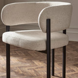 Modern cream fabric dining chair with black metal legs on parquet floor