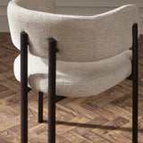 Curved back beige fabric dining chair with black metal legs on parquet floor