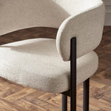 Cream boucle dining chair with black metal legs on wood parquet floor