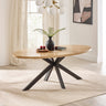 Oval dining table with light wooden top, black intersecting metal legs in bright room setting