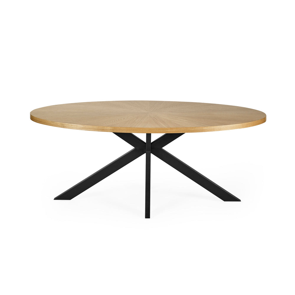 Front view of oval light wood dining table with black metal star-shaped base on white background