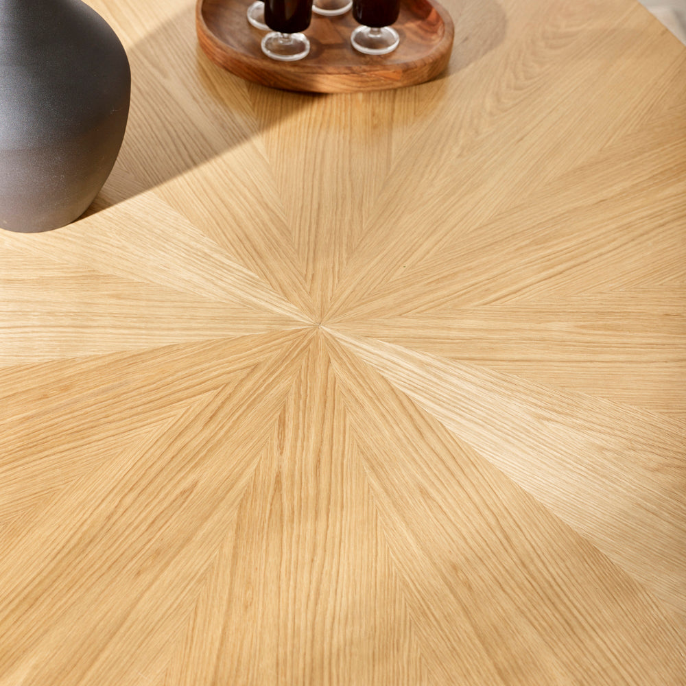 Close-up of light wood dining table surface showing radial wood grain pattern