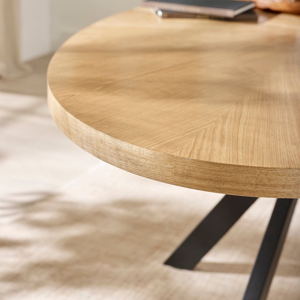 Close-up side view of oval light wood table edge showing wood texture and thickness