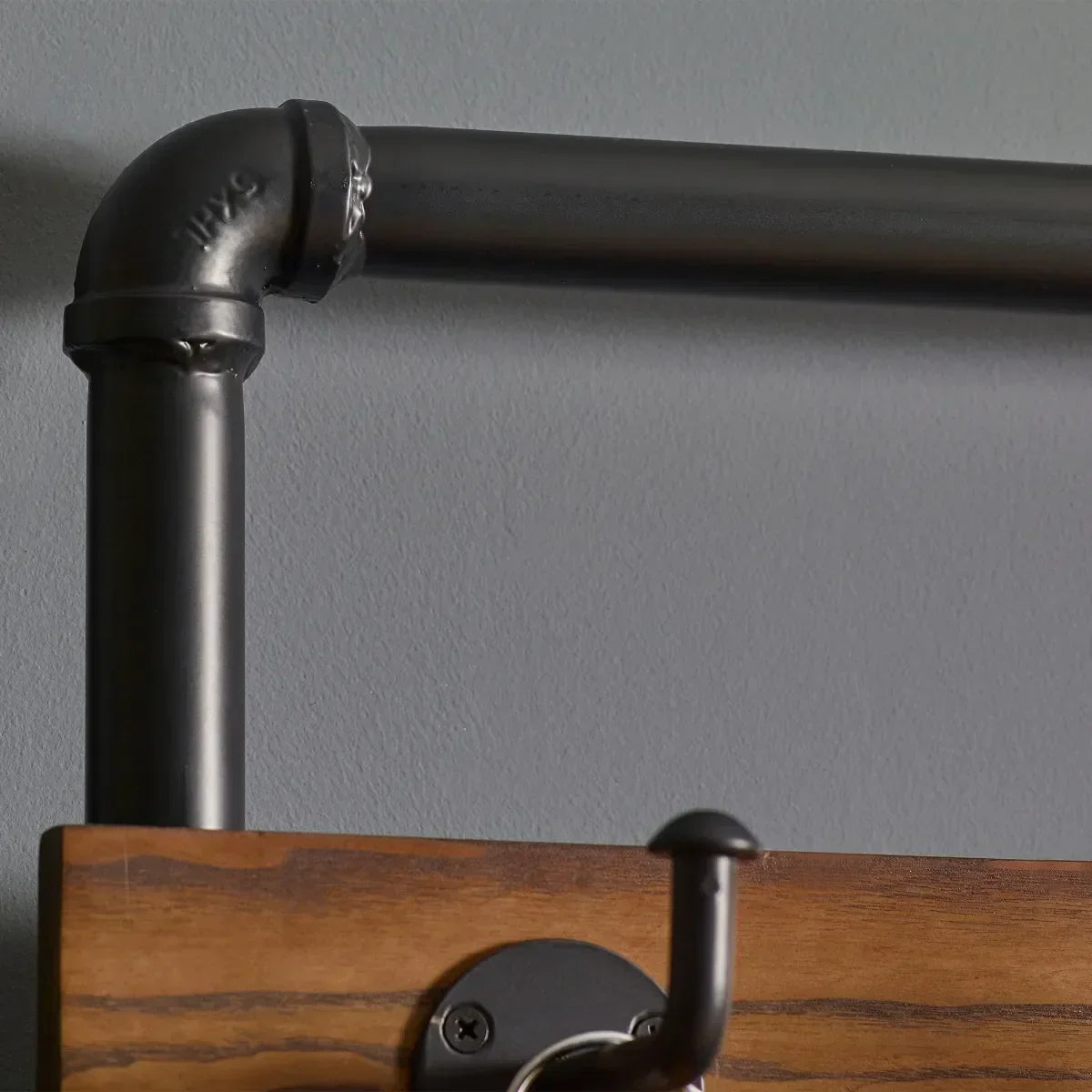 Hallway stand with black metal pipe frame, wood detail, and coat hook against grey wall