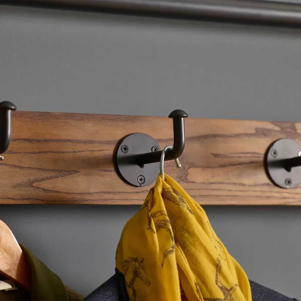 Close up of wooden hallway stand coat hooks with yellow scarf hanging