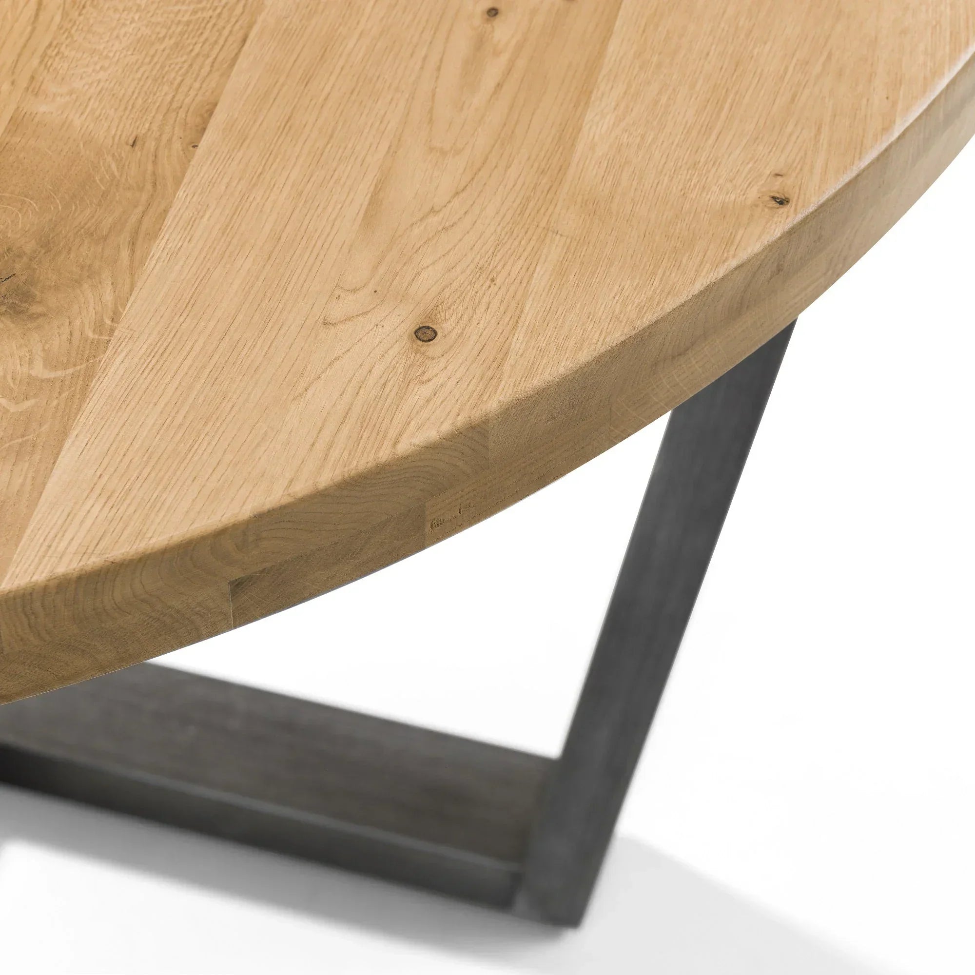 Detail of round oak dining table top with black metal leg