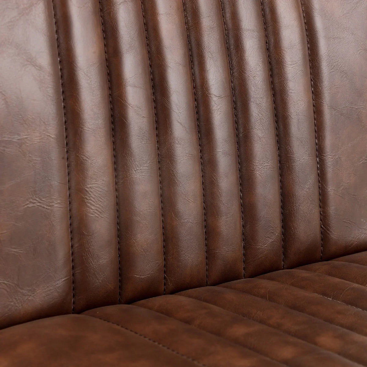 Close view of brown bar stool seat with vertical stitched faux leather upholstery