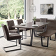 Dark oak dining table with modern metal legs, matching bench and chairs in a bright room