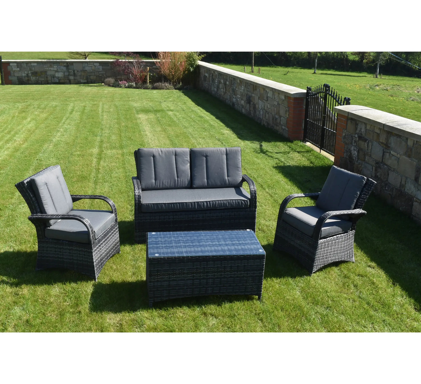 Grey rattan outdoor sofa set with cushioned chairs and coffee table on lawn