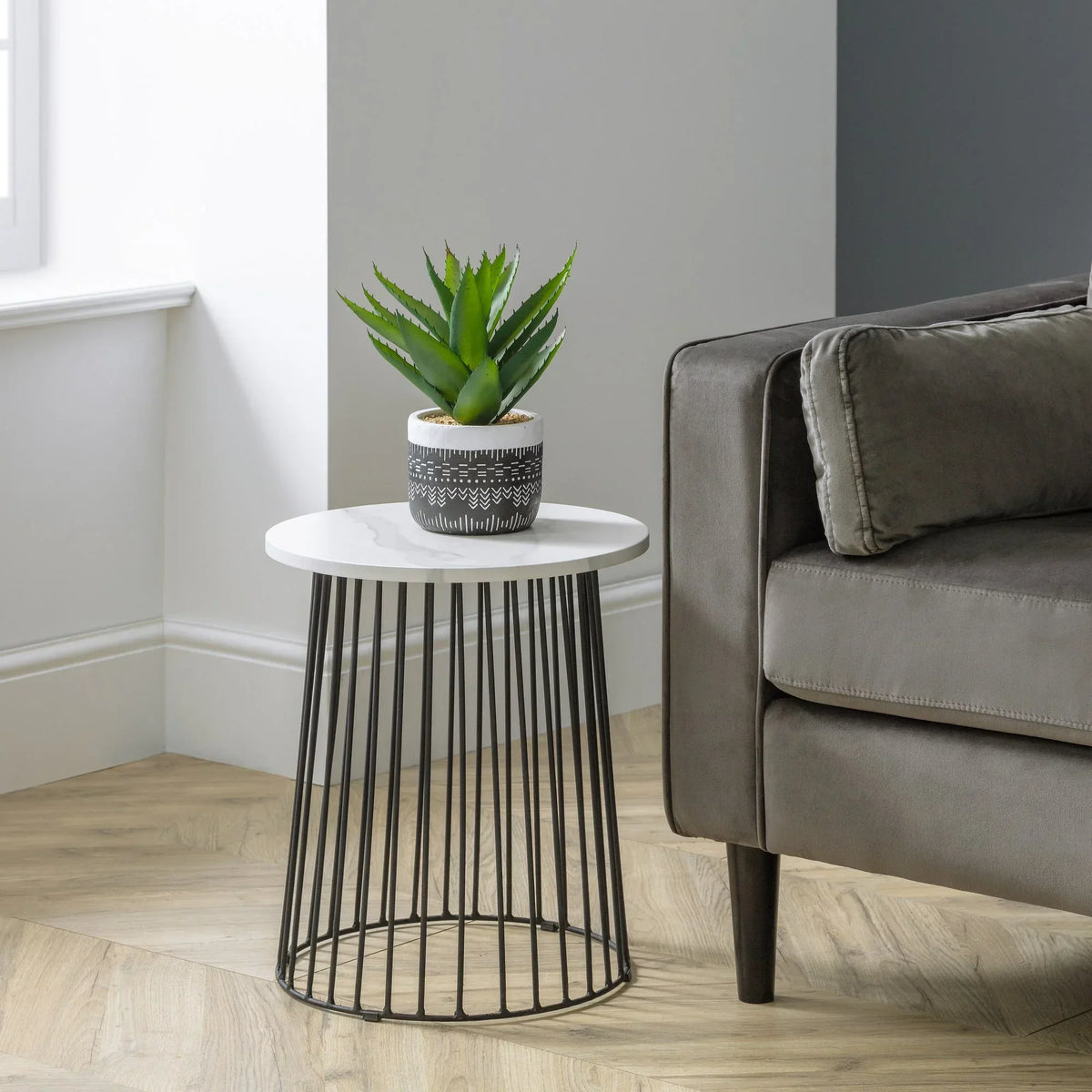 Broadway lamp table with white marble top and black metal base beside grey sofa