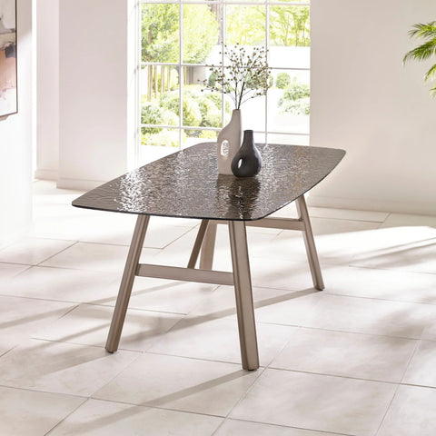 Rectangular glass dining table with textured top and metal legs in bright modern room