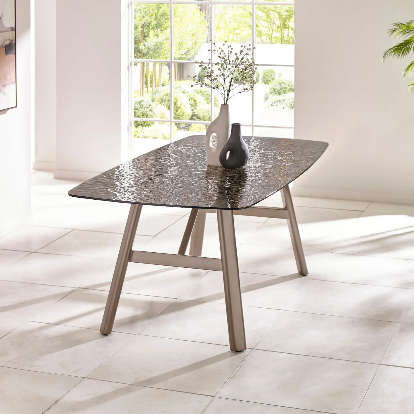 Rectangular glass dining table with textured top and metal legs in bright modern room