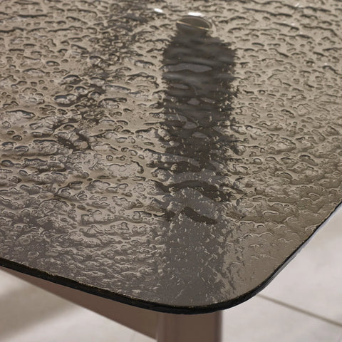 Tempered glass outdoor table top with water droplets, close-up corner view