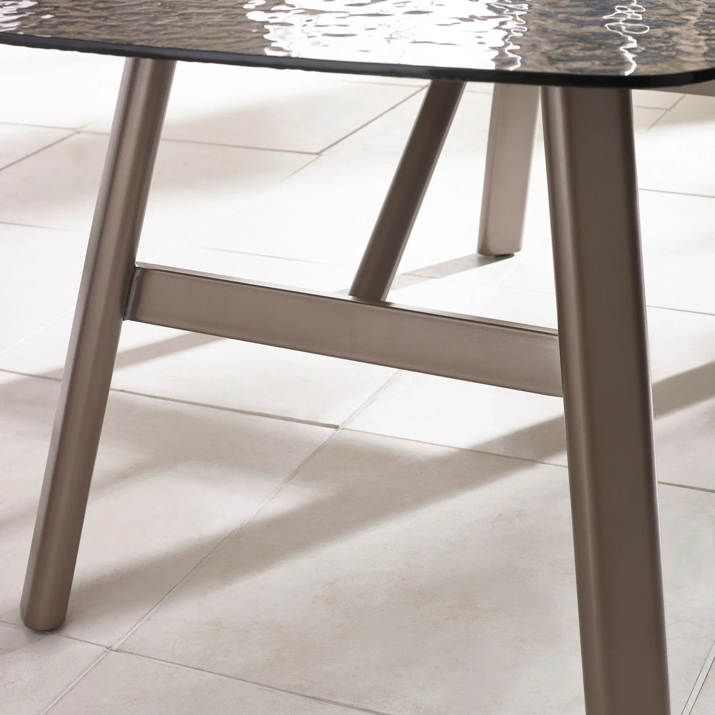 Close view of glass top dining table with metal legs on tiled floor