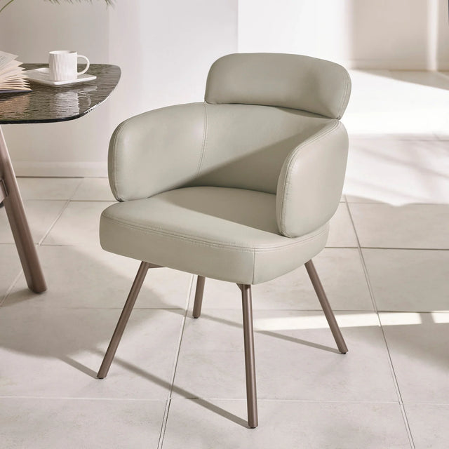 Modern beige leather dining chair with padded backrest and metal legs on tiled floor