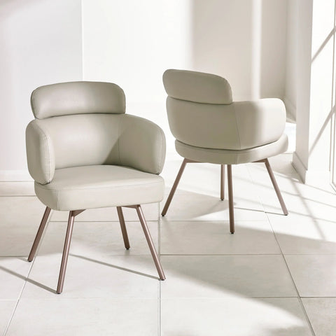 Beige faux leather accent chairs with padded backs and metal legs on tiled floor