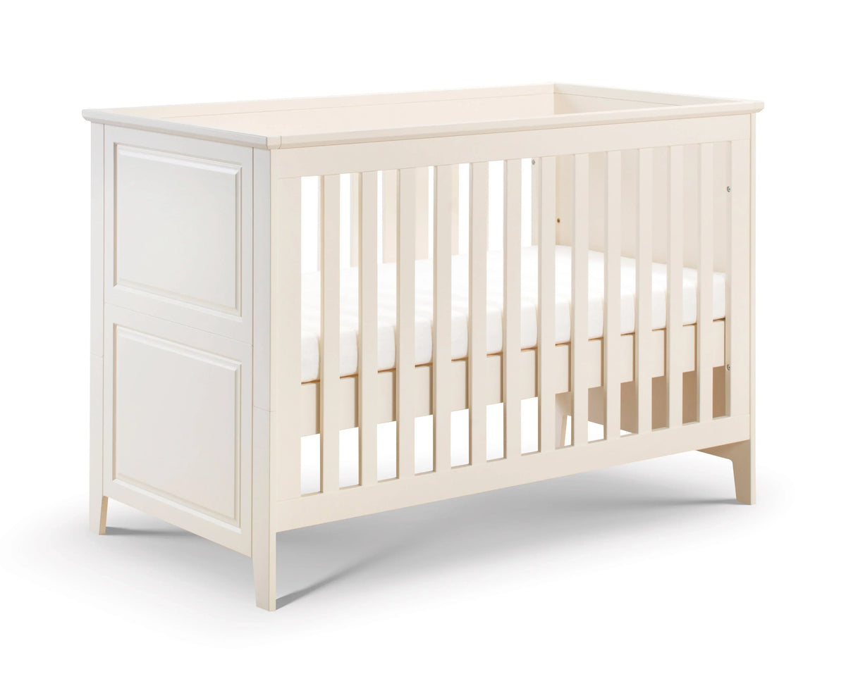 White wood cot bed with panelled headboard and slatted sides on white background