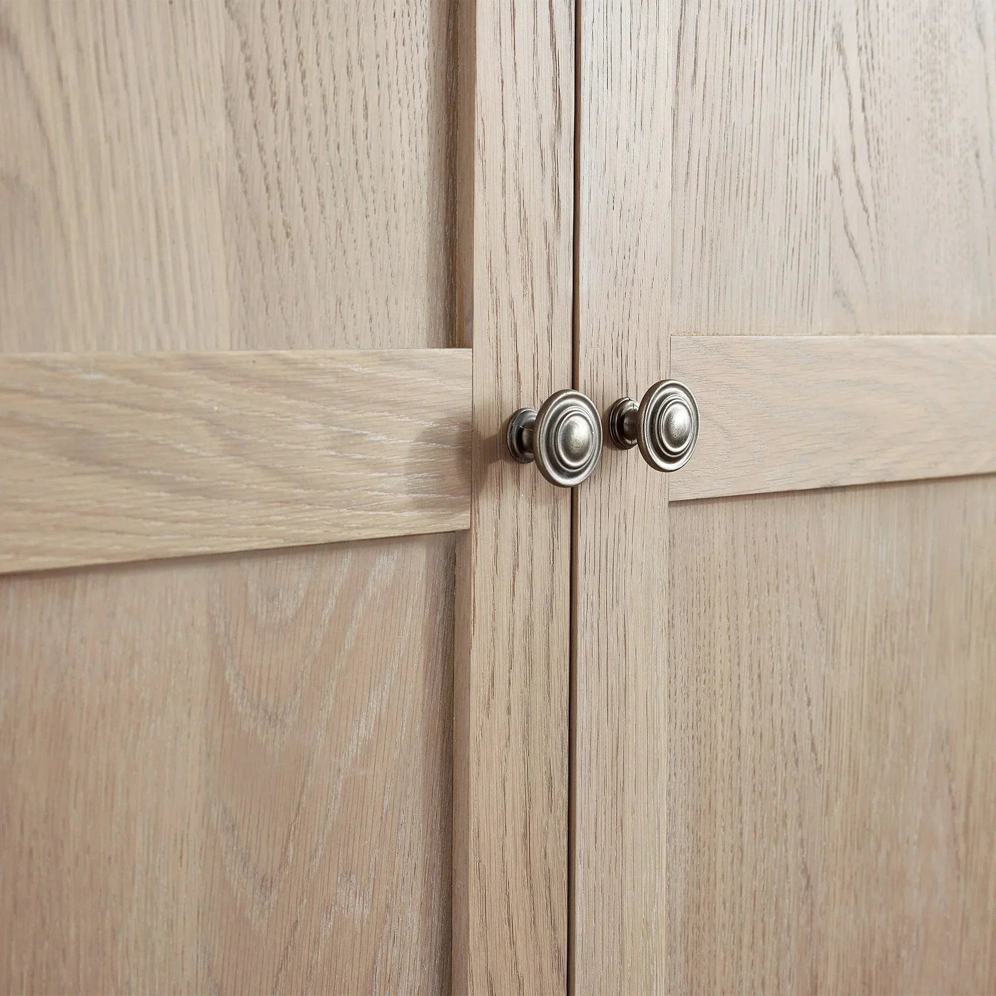 Light oak wardrobe doors with brushed metal knobs and panel detailing