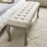Angled top view of beige button tufted fabric bench with natural wood cabriole legs on cream rug
