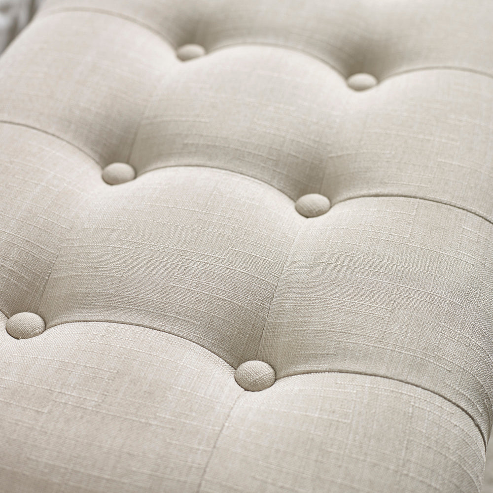 Close up detail of beige button tufted fabric upholstery with subtle linen texture on bench seat