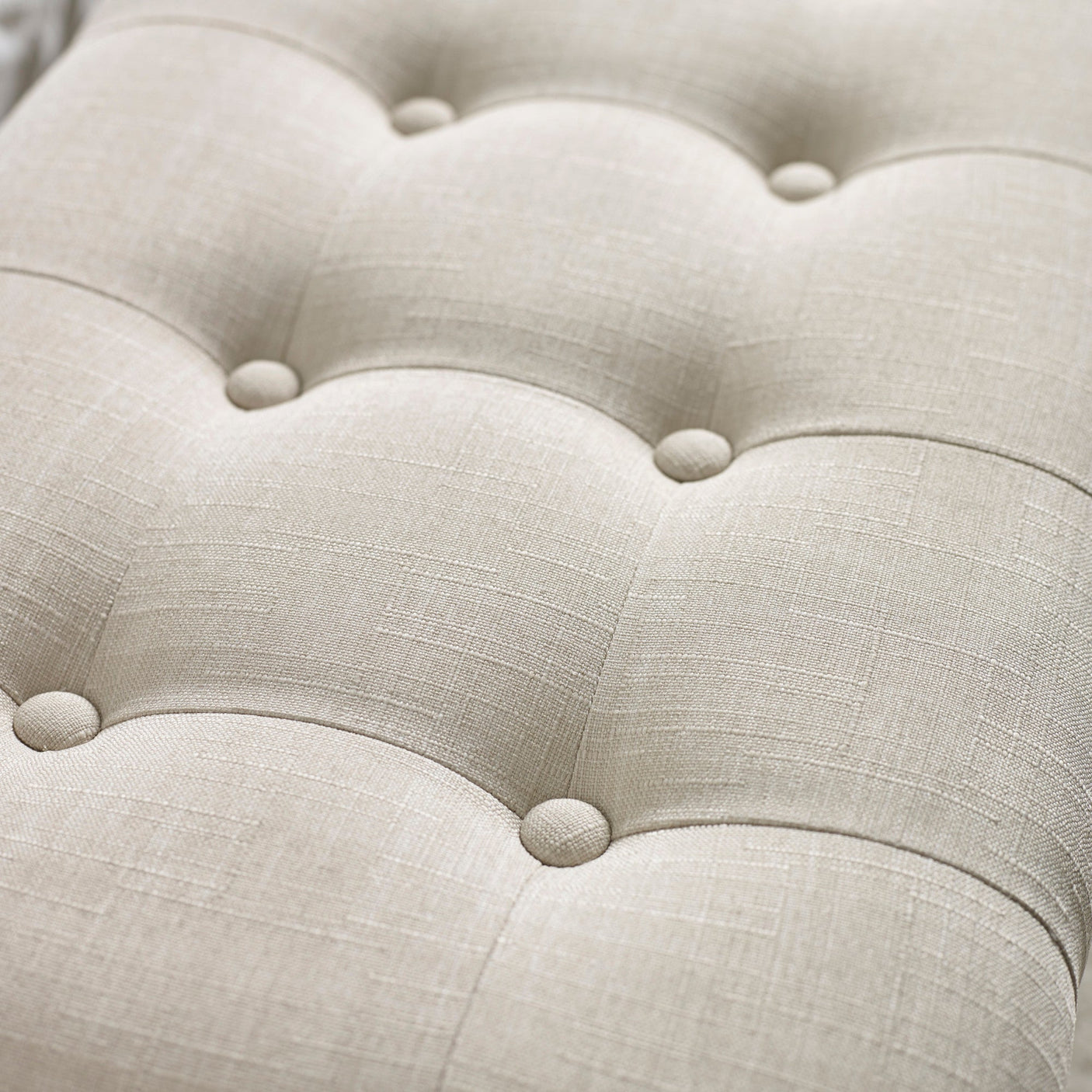 Close up detail of beige button tufted fabric upholstery with subtle linen texture on bench seat