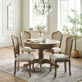 Round extending wooden dining table with four beige cushioned cane-back chairs in bright room
