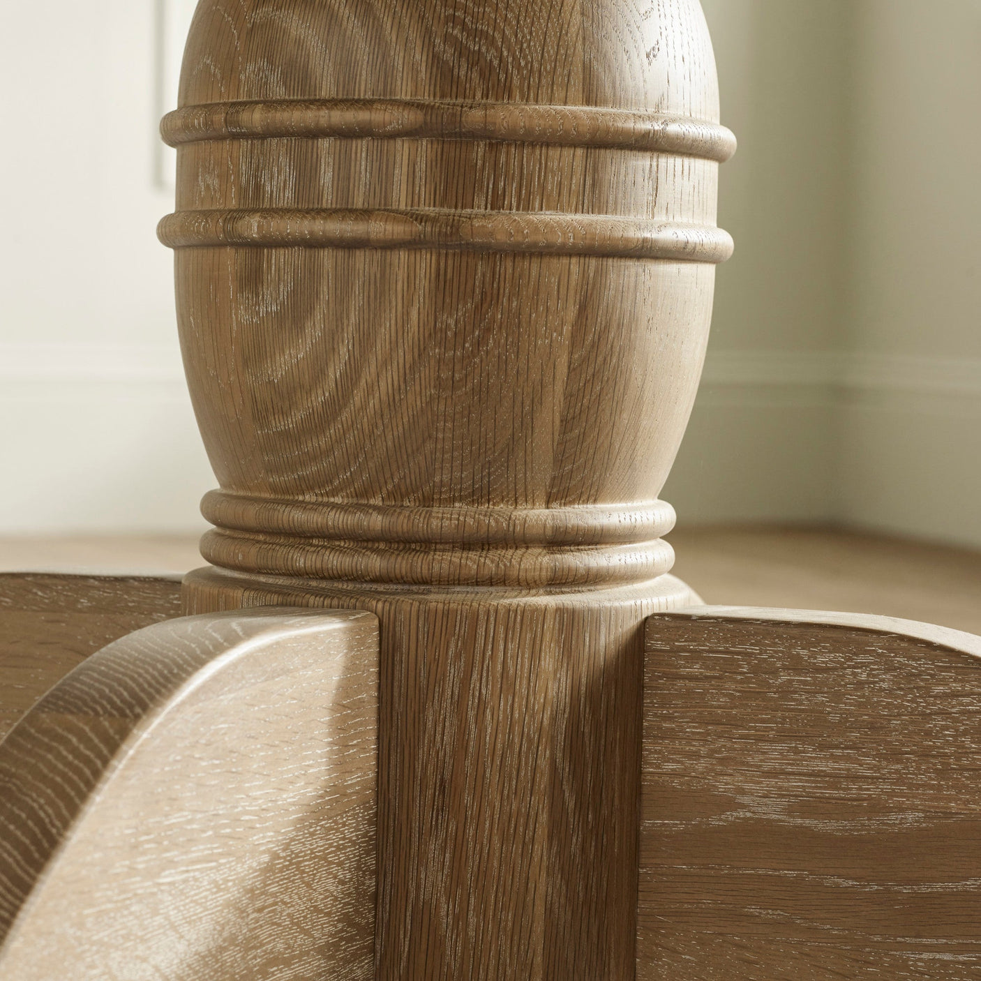 Close-up of light oak round table pedestal base with carved detailing and grain texture
