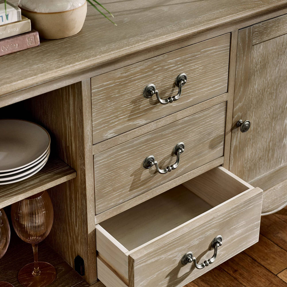 The Camille French Style 2 Door 2 Drawer Sideboard in limed oak features a textured finish with elegant metal handles, showcasing a blend of functionality and classic design, perfect for a dining or living room setting