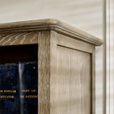 The Camille French Style Tall Bookcase features a limed oak finish with a textured surface, showcasing its elegant design and sturdy construction, perfect for displaying books and decorative items in a stylish living space