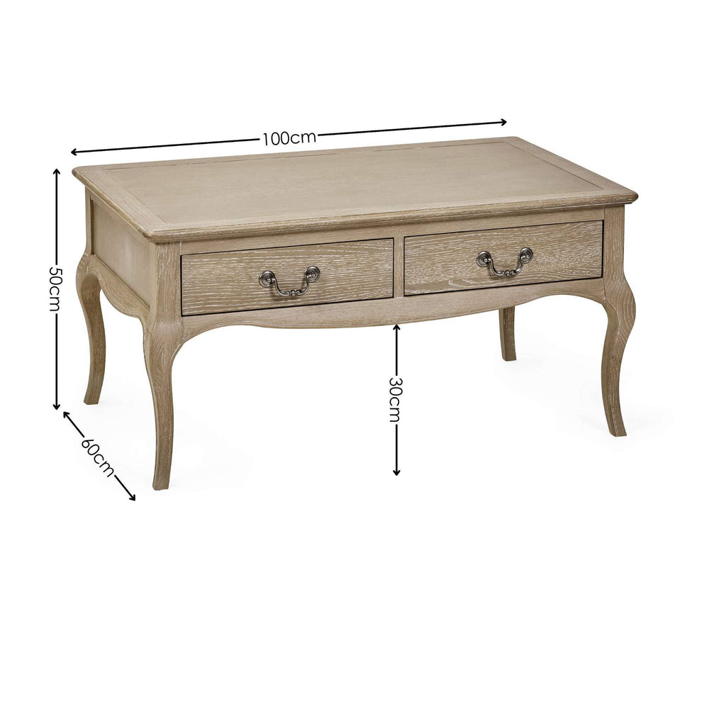 The Camille French Style Rectangular Coffee Table in limed oak features a smooth top, two decorative drawers with metal handles, and elegantly curved legs, perfect for enhancing a cozy living room setting