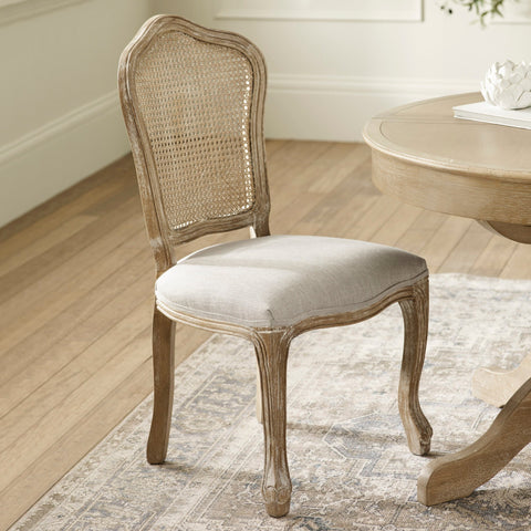 Single beige dining chair with rattan backrest and light wood frame on patterned rug by round wood table