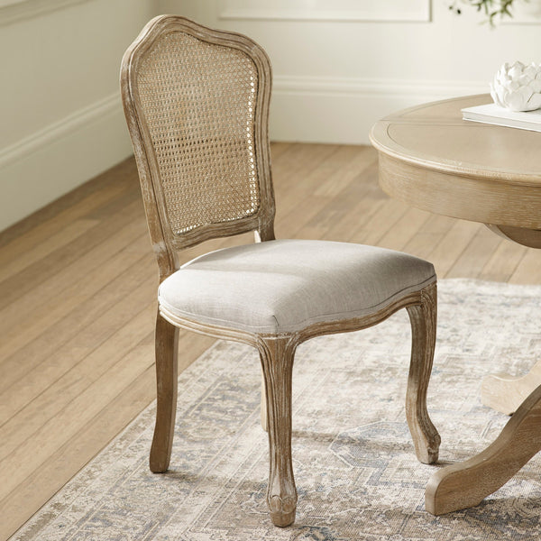 Single beige dining chair with rattan backrest and light wood frame on patterned rug by round wood table