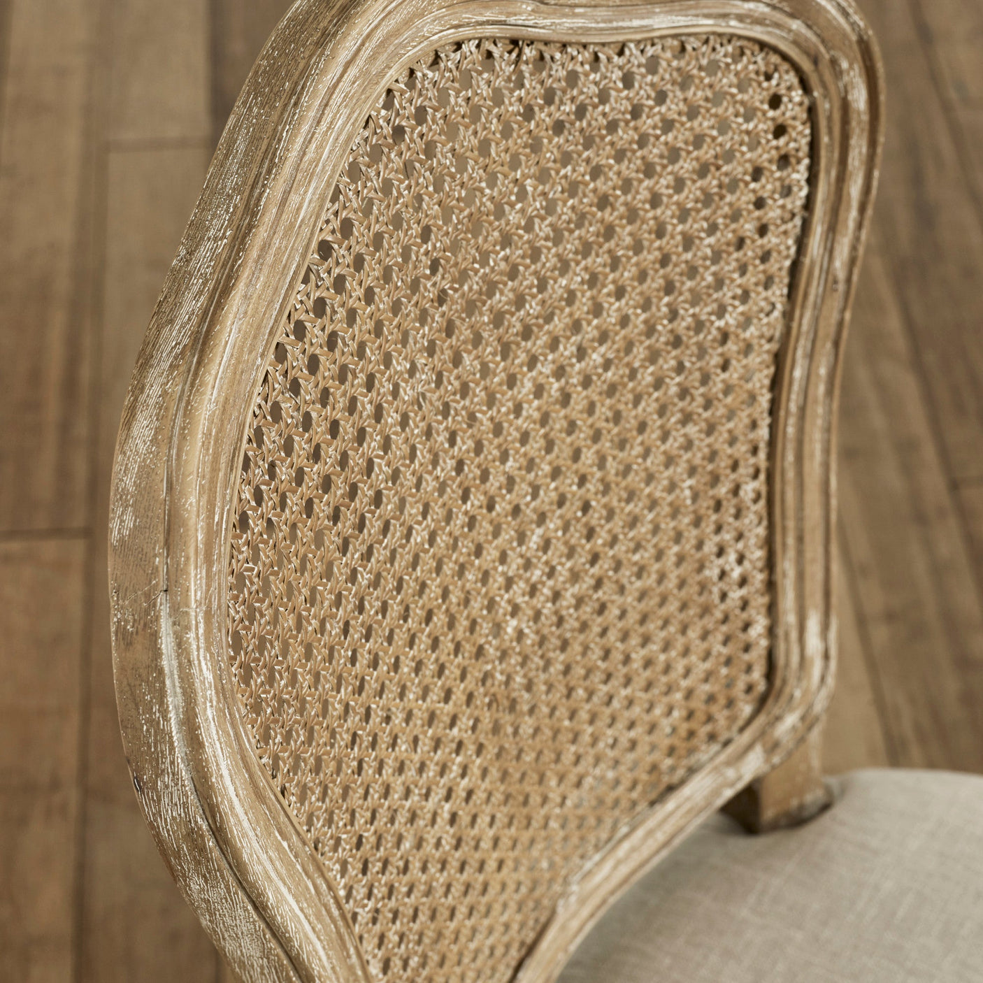 Close-up of rattan woven backrest and weathered light wood frame of beige dining chair