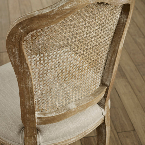 Close-up of side and back of beige rattan dining chair with weathered light wood frame and upholstered seat