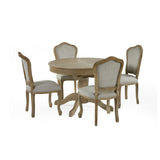 Round wooden dining table surrounded by four beige upholstered dining chairs, two with cane backs on white background.
