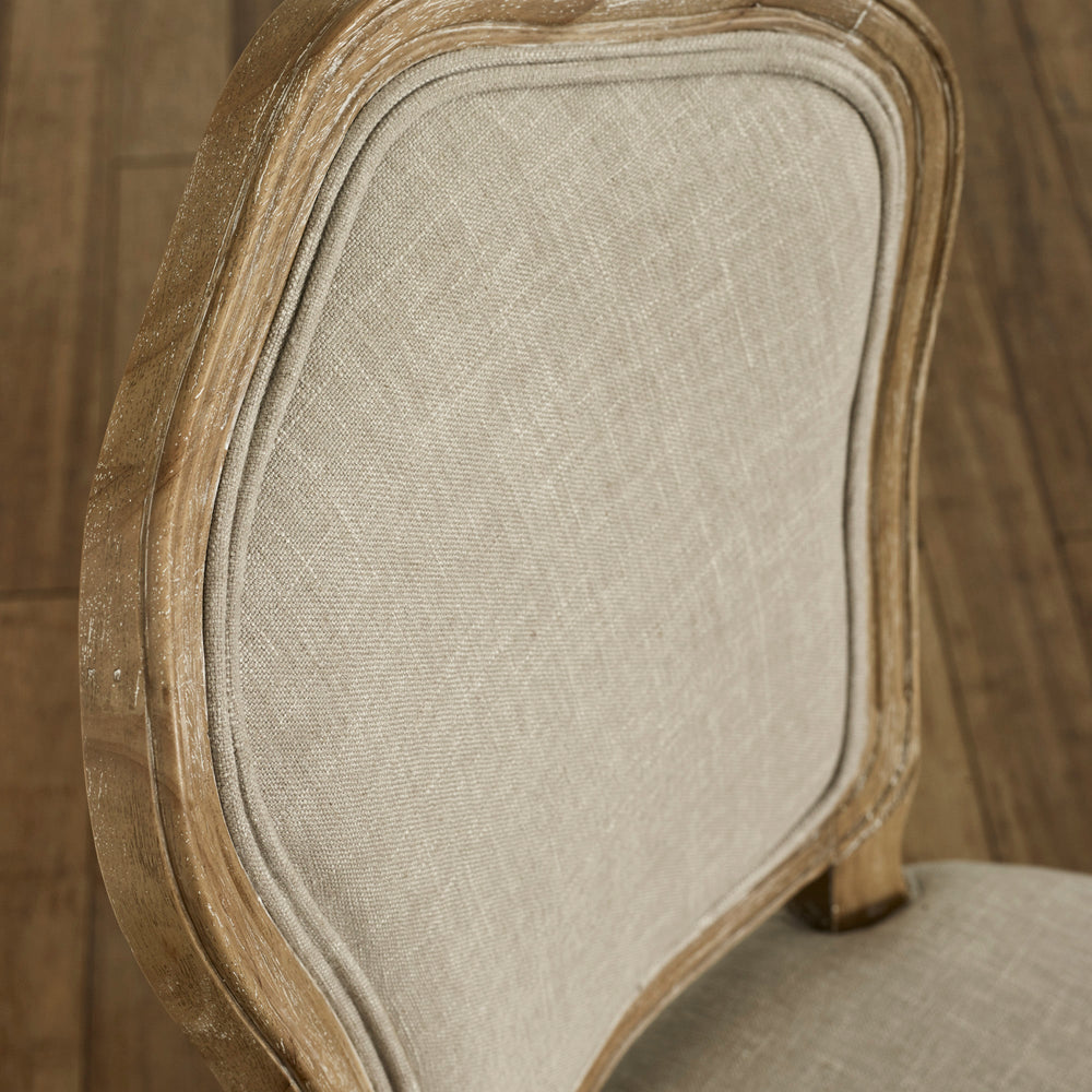 Close-up of beige upholstered dining chair backrest with weathered natural wood frame detail