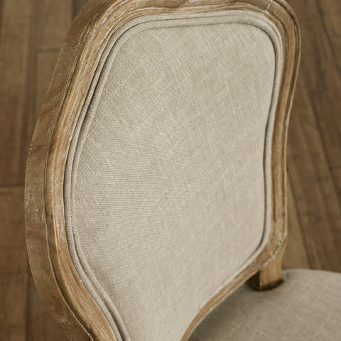 Close-up of beige upholstered dining chair backrest with weathered natural wood frame detail