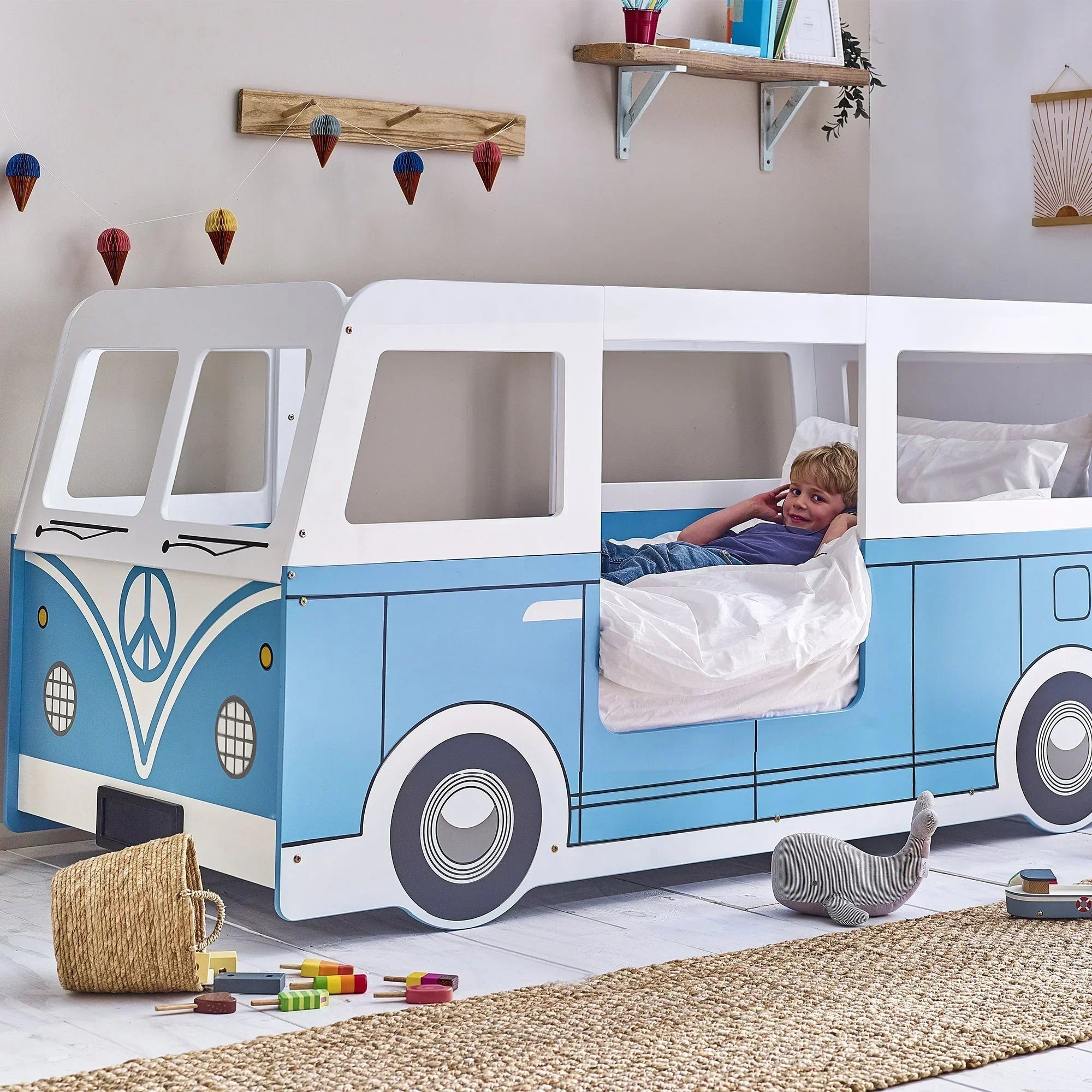 Blue campervan kids bed with a child relaxing in a playful bedroom setting