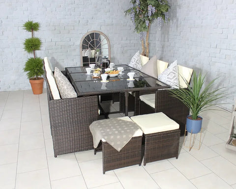 Brown rattan dining set with cream cushions and glass table, arranged with breakfast setting indoors